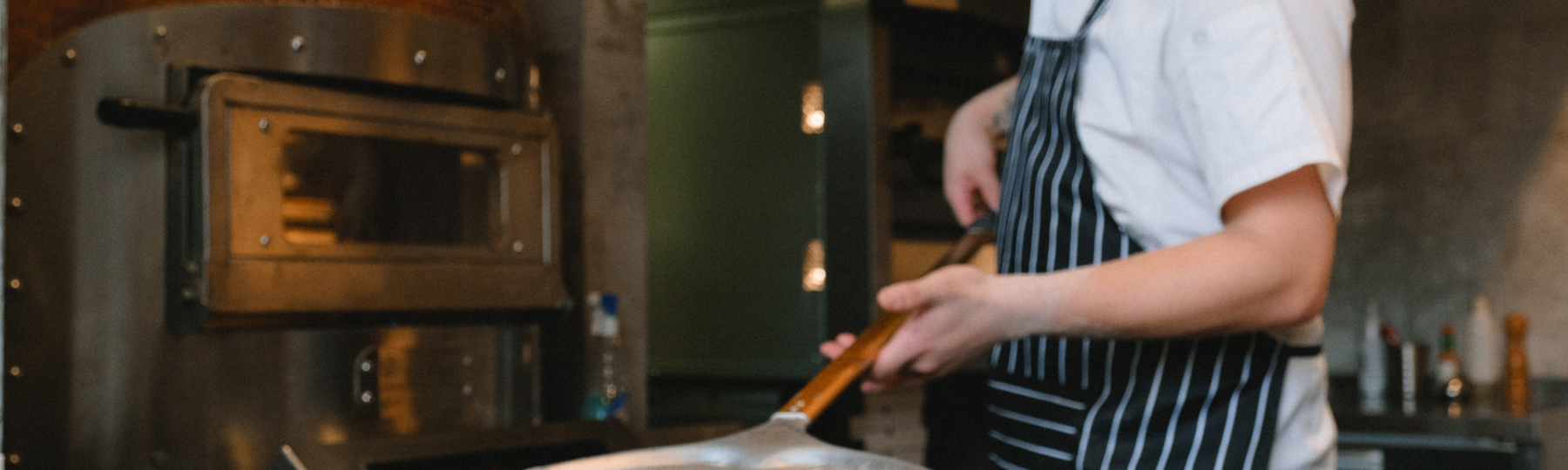 An image of a chef working with a pizza oven.