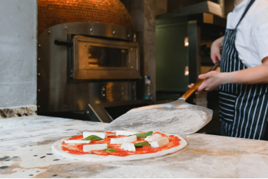 An image of a chef working with a pizza oven.